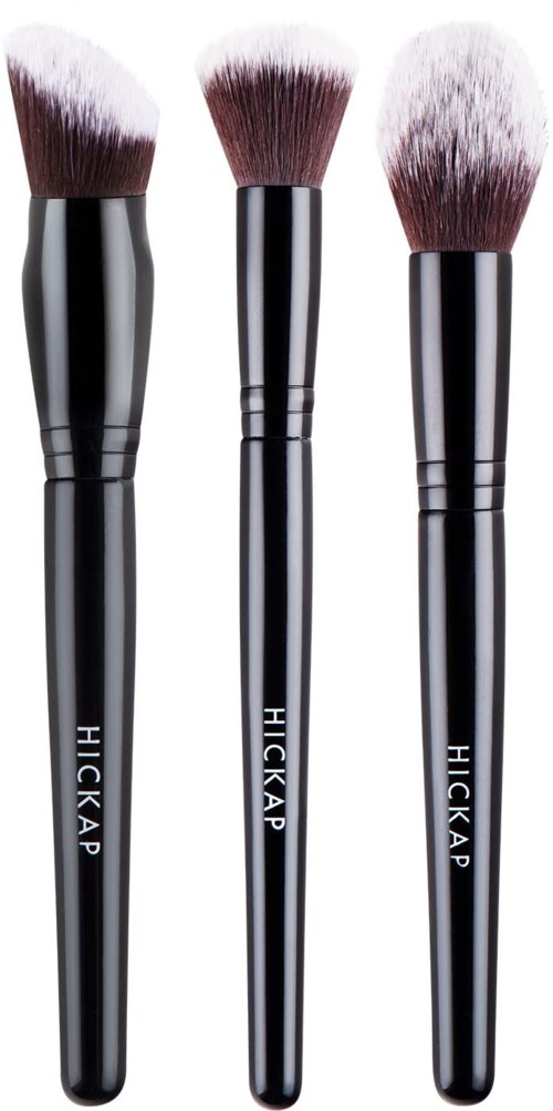 Three black makeup brushes with white and brown bristles stand in a row. The brushes have the brand name Hickap on handles.
