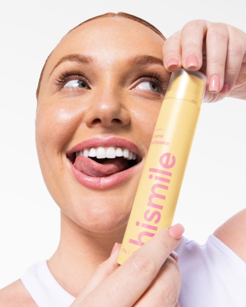 A woman is smiling and sticking out her tongue while holding a yellow product labeled "chrismaile."