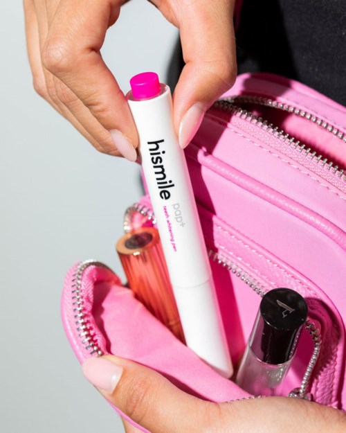 A person puts a pink lipstick and a lip balm labeled 'hismile' into a pink bag.