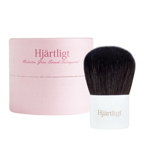 A pink round box and a large makeup brush with a white handle labeled 'Hjärtligt'.