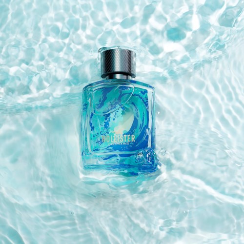 Een flesje cologne drijft in helder water, met een zilveren dop en blauwe vloeistof.