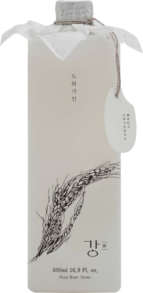 Eine weiße Flasche mit koreanischem Text, einer schwarzen Illustration und einem angehängten Papieretikett. Sie ist als Reiskleie-Toner gekennzeichnet.