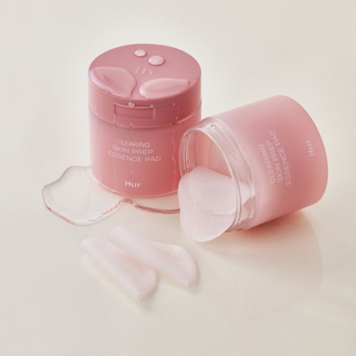 Twee roze containers met huidvoorbereidingspads, een open met padstukken eromheen, op een wit achtergrond.