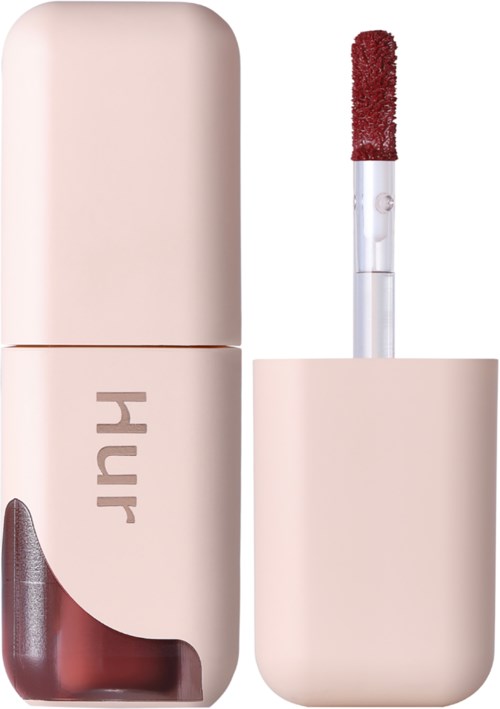 Een lippenstift met applicator in een lichtroze doos met tekst.