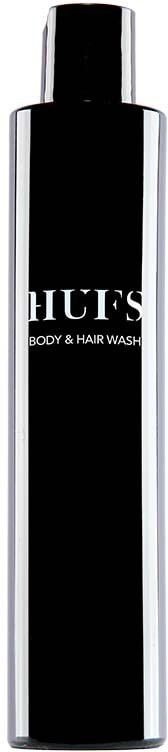 Eine lange schwarze und silberne Flasche mit einem Etikett, das 'HUF'S BODY & HAIR WASH' sagt, steht senkrecht.