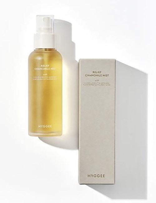 A yellow bottle labeled 'Relax Chamomile Mist' next to a white box with the same label inside. Shadows cast on white background.