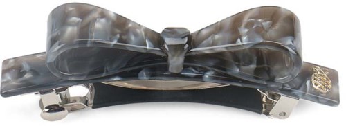 A hair clip with a shiny, marbled bow design and metal clasp. It has a small decorative charm on the side.