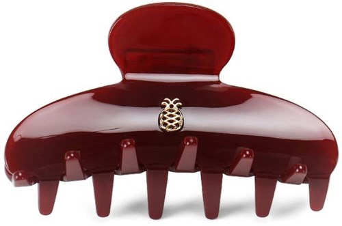 A large red hair clip with a small decorative gold pineapple in the center.