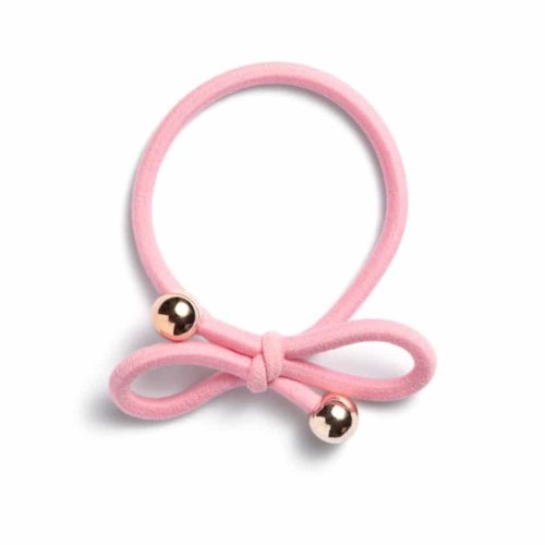 A pink hair tie with two gold-colored balls and a small bow.