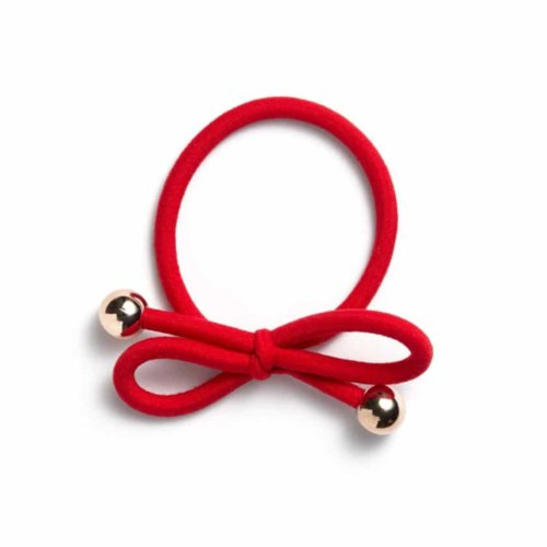 A red hair tie with a small bow and two silver balls on each end.