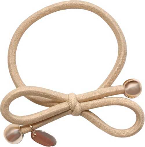 A beige hair tie with a bow and pearl decorations, with a small charm hanging from one part.