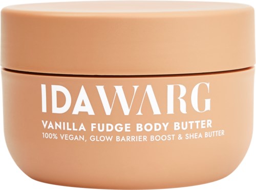 A round, peach-colored jar of IDAWARG Vanilla Fudge Body Butter, featuring white text about vegan ingredients and shea butter.