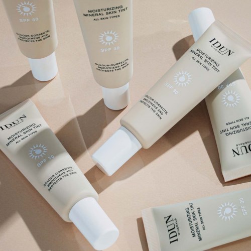 Cremetuben mit Feuchtigkeitscreme und SPF 30, verteilt auf Oberfläche, Etikett zeigt Sonnen-Symbol und Produktdetails.
