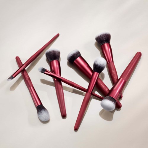 Ein Set rosa Makeup-Pinsel mit grauen und weißen Borsten liegt auf einer weißen Oberfläche.