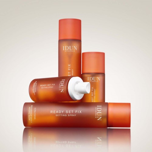 Four orange spray bottles and tubes with white text, labeled IDUN, arranged with one lying down and three standing.