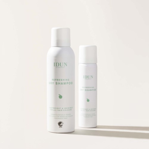 Två vita flaskor märkta IDUN Refreshing Dry Shampoo, med grön text och ett litet grönt blad, på en vanlig bakgrund.