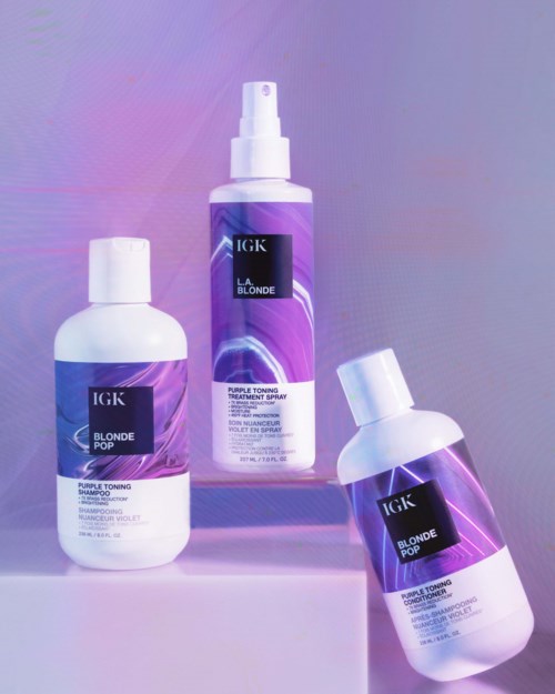 Tre flasker med hårpleieprodukter fra IGK, merket 'Blonde Pop' og 'La Blonde', på en pastellbakgrunn.