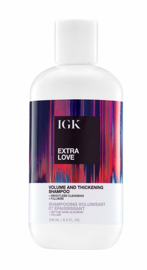 Eine weiße Flasche mit IGK Extra Love Shampoo für Volumen und Verdickung, mit einem bunten gestreiften Etikett.
