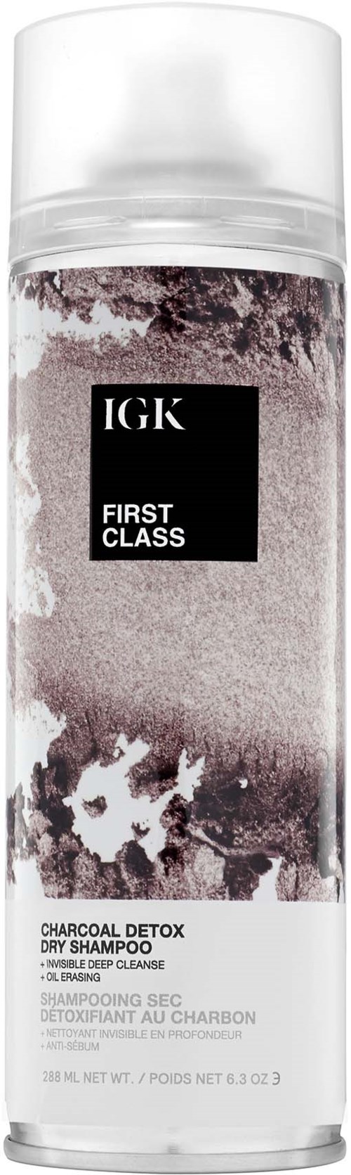 Det er en gjennomsiktig sprayflaske som inneholder charcoal detox tørrsjampo fra IGK, merket 'First Class.'