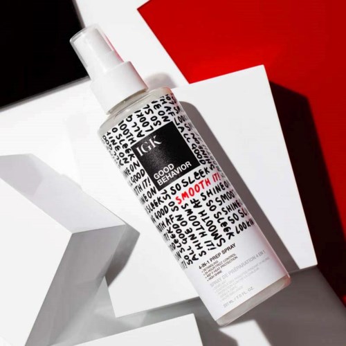 Eine weiße Sprühflasche mit schwarzen und roten Texten, liegt auf weißen und roten Hintergründen.