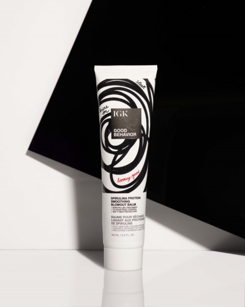 Eine Tube Hautcreme mit schwarzem und weißem Wirbelmuster, vor schwarzem und weißem Hintergrund. Marke ist IGK.