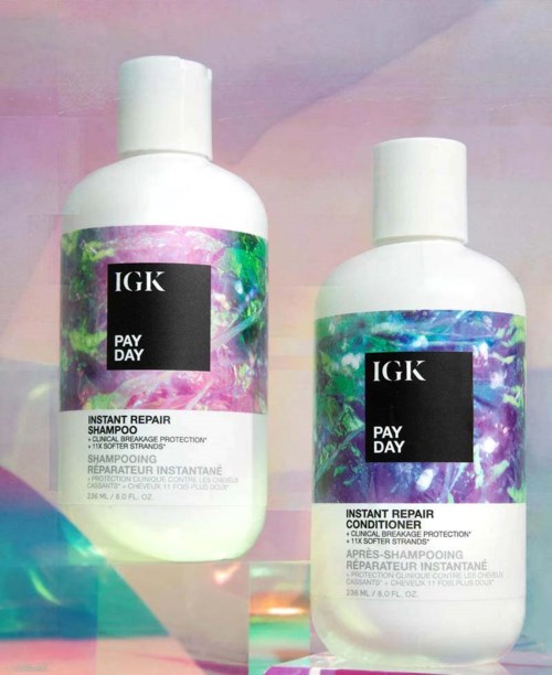 Twee witte flessen IGK Pay Day haarproducten, shampoo en conditioner, met kleurrijke, glanzende labels.