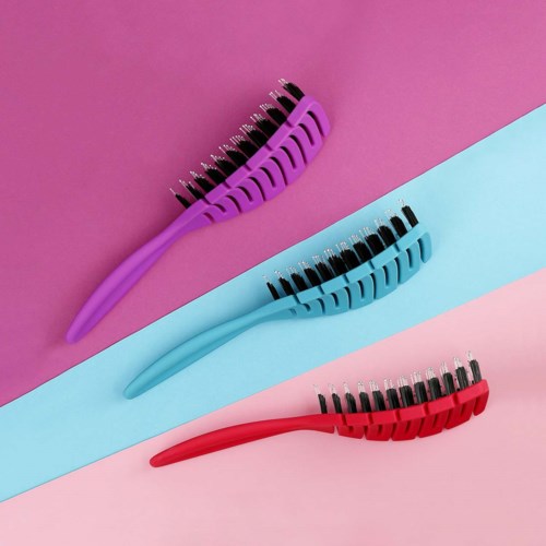 Three colorful hairbrushes with black bristles on pink, blue, and purple backgrounds.