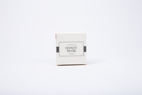 Een kleine doos met 'Honey Mask' op de plek, met een eenvoudig ontwerp, op een witte achtergrond.