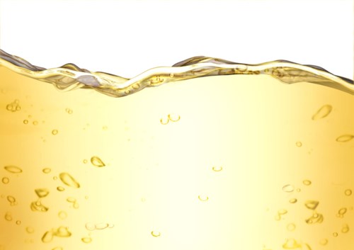 Orangenfarbene Flüssigkeit mit Bläschen, eventuell Softdrink oder Saft, vor weißem Hintergrund.