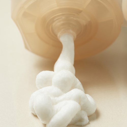 A bottle is pouring white foam or whipped cream onto a surface.