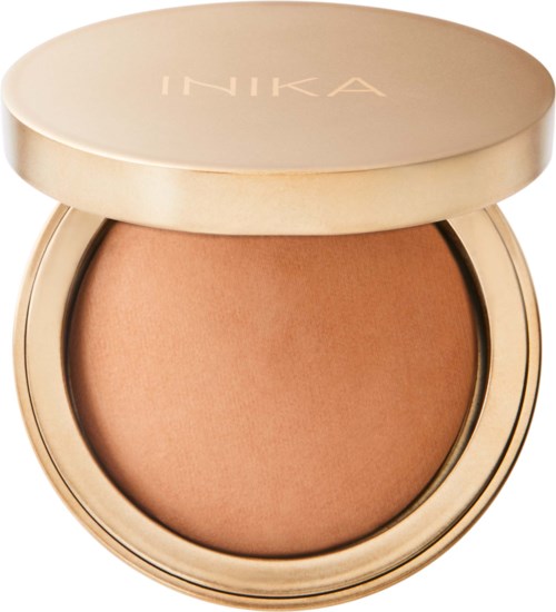 Meikkipakkaus, jossa vaalean beige jauhe ja kultainen kansi, jossa lukee 'INIKA'.