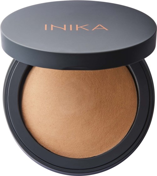 Ett kompakt puder i ett svart behållare med stängd lock med "INKA" skrivet på.
