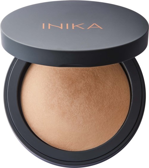 A compact of pressed powder foundation with a black case and a lid that says INIKA.