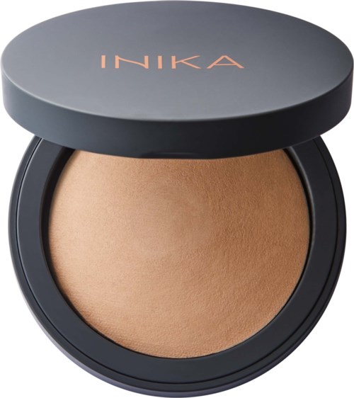 A compact of pressed powder makeup with the brand name 'INIKA' on the lid.