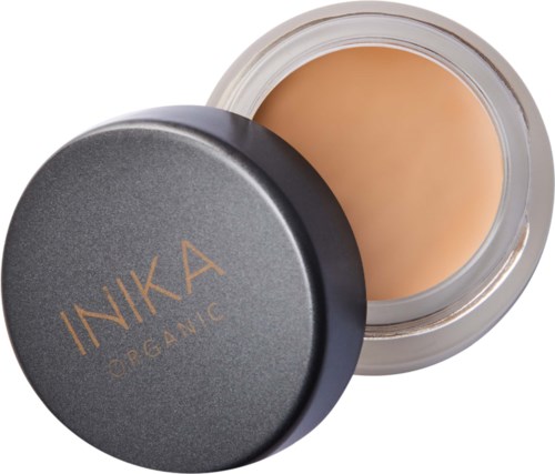A round container of foundation with a black lid that has gold text reading "INIKA ORGANIC."