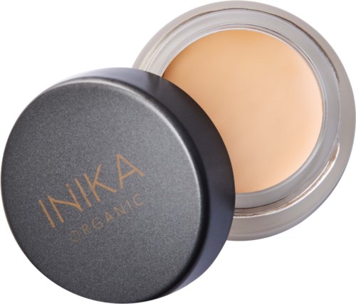 A round glass jar with beige cream inside and a black lid labeled 'INIKA ORGANIC'.