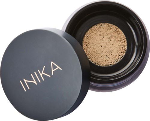 En rund mörk behållare med lock som visar lös puder inuti, märkt INIKA.