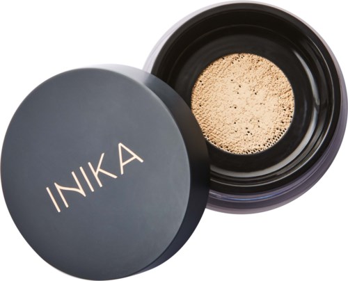 Black container with a beige powder inside, labeled INIKA. It appears to be makeup or cosmetic product.