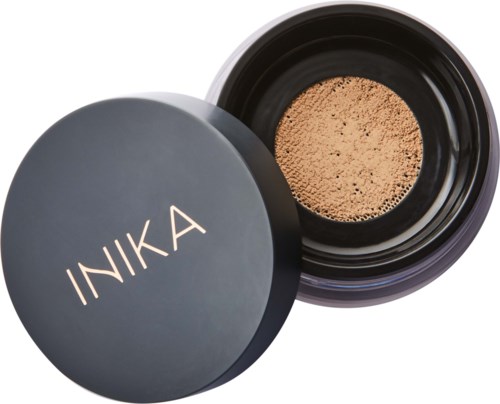 A round black container with a lid that says INIKA, holding powder, possibly makeup or face powder.
