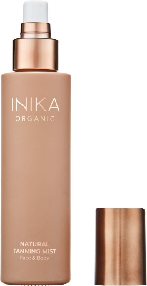 En beige flaske med hvit sprayhette og en kobberfarget hette ved siden av, merket 'INIKA Organic Natural Tanning Mist'.