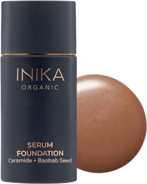 Tummansininen pullo, jossa lukee 'INIKA Organic Serum Foundation', ja sen vieressä ruskea munanmuotoinen esine.