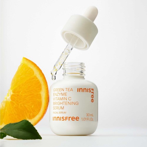 En ansiktsserum med ingredienser som apelsin, citron och grönt te i en vit flaska med pipett.