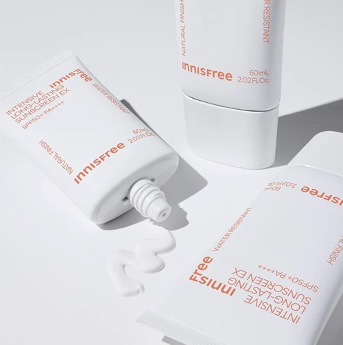 Twee witte tubes van Innisfree zonnebrandcrème, één open en lekt crème, op een witte achtergrond.