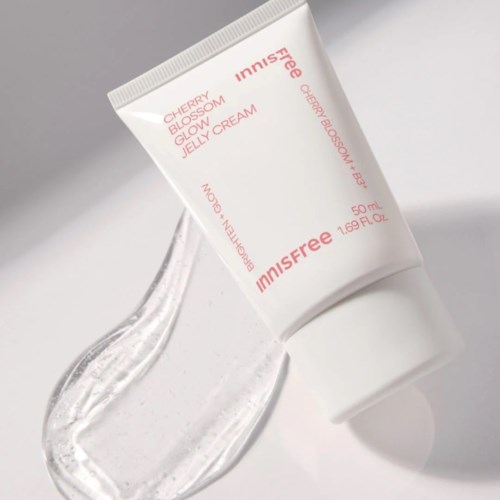 Een witte tube met Jeju Blossom Jelly Cream met roze en oranje tekst ligt op een witte ondergrond.