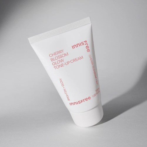 Een witte tube met de tekst 'Innisfree Cherry Blossom Glow Tone Up Cream' op een eenvoudige achtergrond.