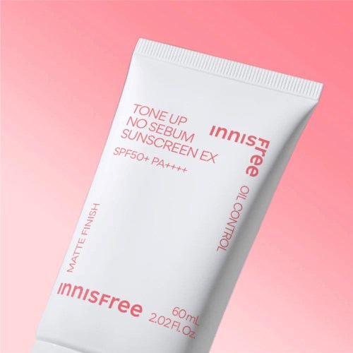 En vit tub med solskyddsmedel med rosa text, visar SPF 50+ skydd, placerad på en rosa bakgrund.