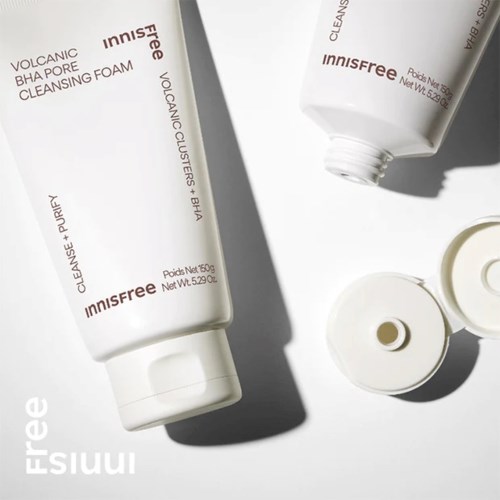 Kaksi valkoista Innisfree-meikkatuotteiden putkea, toinen ilman kantta, valkoisella pinnalla varjoineen.
