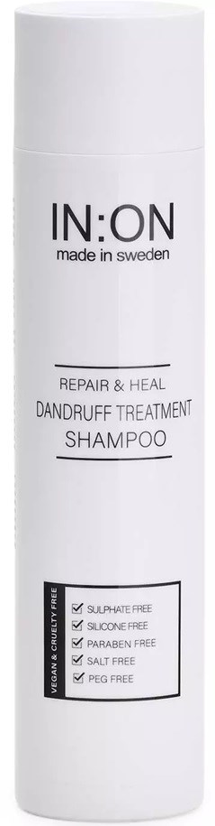 A tall, white bottle labeled IN:ON Repair & Heal Dandruff Treatment Shampoo, free from sulfates, silicones, parabens, salts, and PEG.