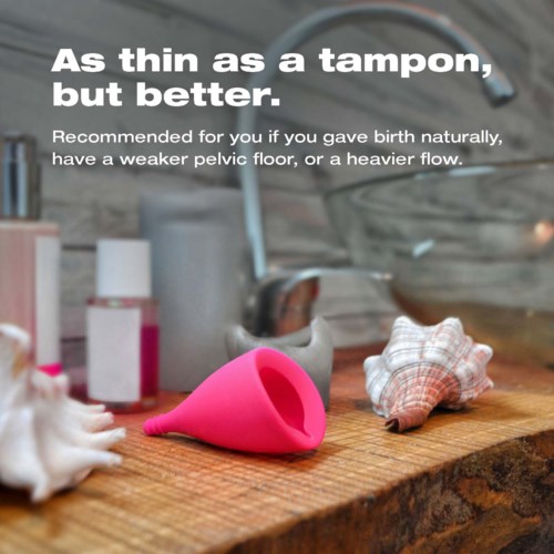 Ein Menstruationstempel, Seife und Stoffe auf einer Holzoberfläche mit Wasserhahn im Hintergrund. Text erklärt, dass Menstruationstassen besser sind.
