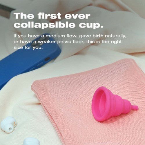Text beschreibt eine zusammenklappbare Menstruationstasse, mit einer pinken Tasse auf rosa Stoff und Hörhilfen in der Nähe.